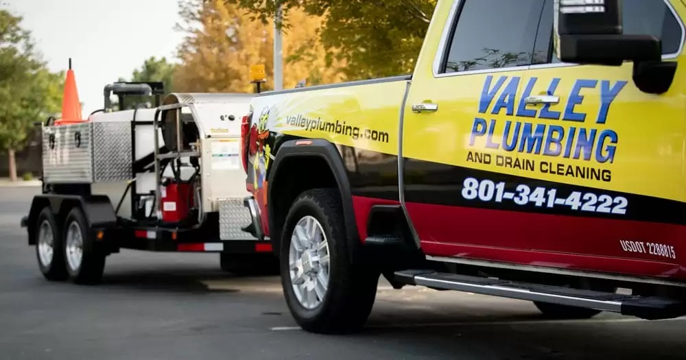 Valley Plumbing technician operating a hydro jetter from a truck-mounted unit at an Orem home