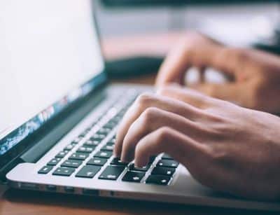 Researching professional plumbers online. Close up of typing on a laptop.