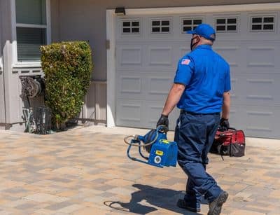 professional plumber with tools walking toward home