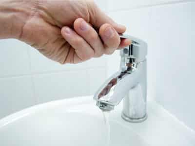 Close up of man hand turning off bathroom faucet